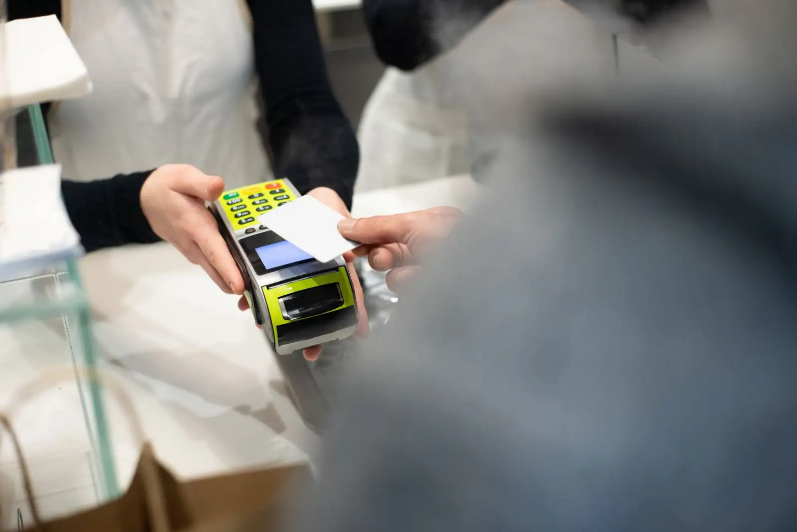 Client réglant un achat par carte sans contact sur un terminal de paiement, en magasin.