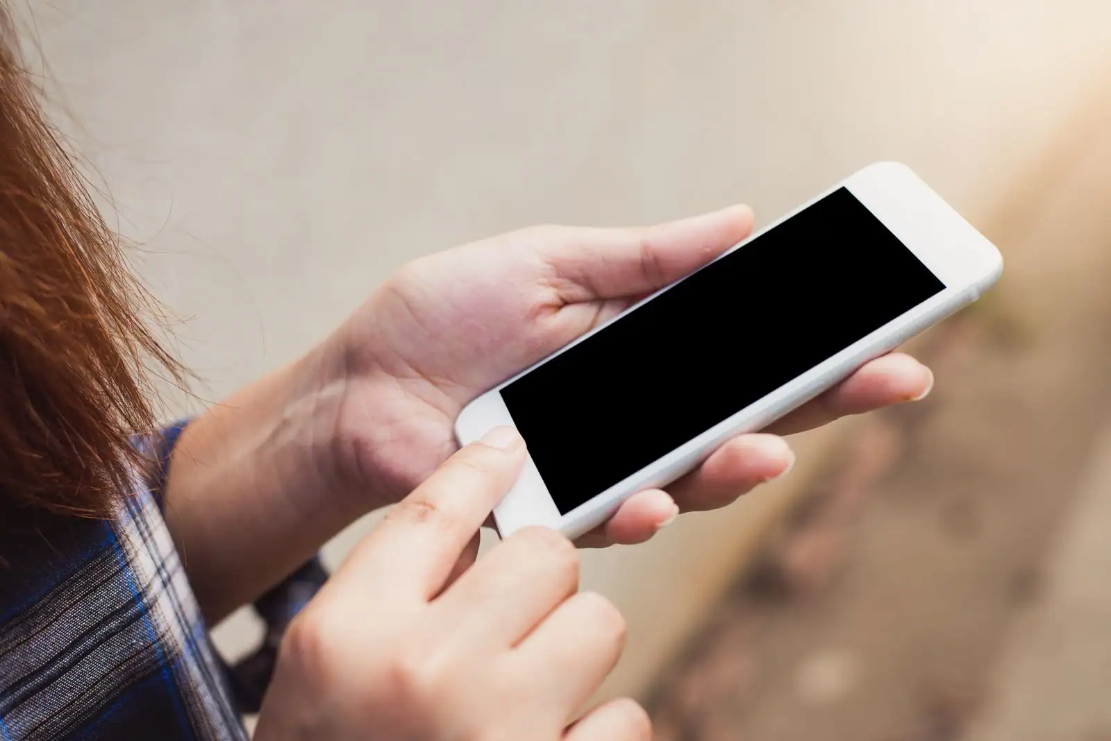 Personne tenant un smartphone et touchant l'écran du doigt, image illustrative de la banque en ligne.