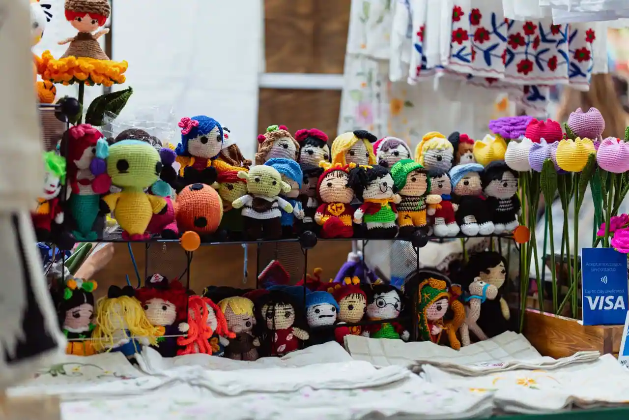 Poupées et petits jouets colorés faits main exposés sur l'étal d'un stand de marché.