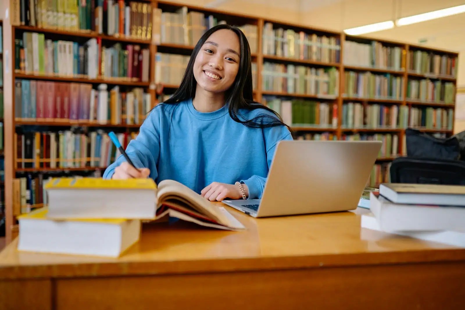 Étudiante travaillant sur un ordinateur portable avec des cahiers dans une bibliothèque
