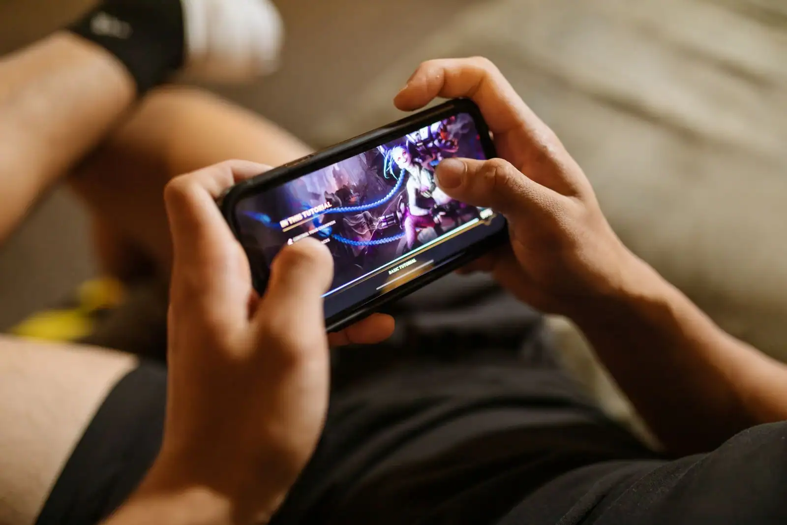 Personne jouant à un jeu sur l'écran de son smartphone, tenu à deux mains.