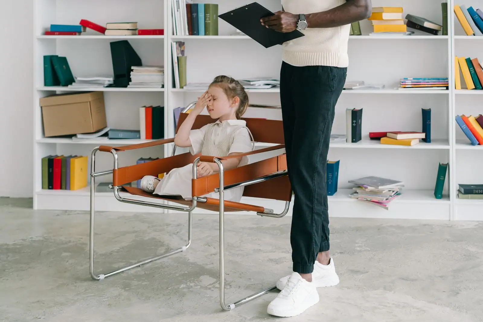 Séance d'accompagnement d'une jeune enfant par un intervenant tenant un porte-bloc, dans un bureau