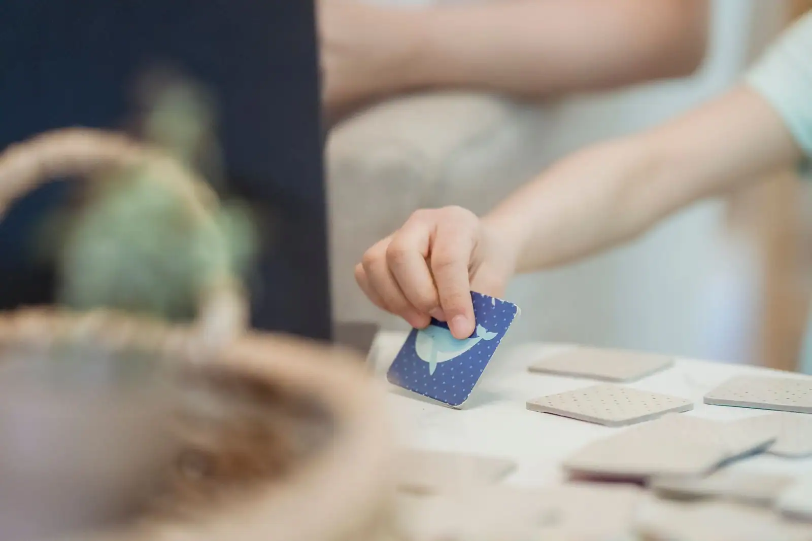 Main d'enfant choisissant une carte illustrée parmi des cartes posées sur une table