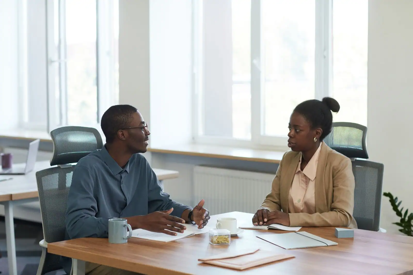 Deux collègues en conversation attentive dans un bureau lumineux