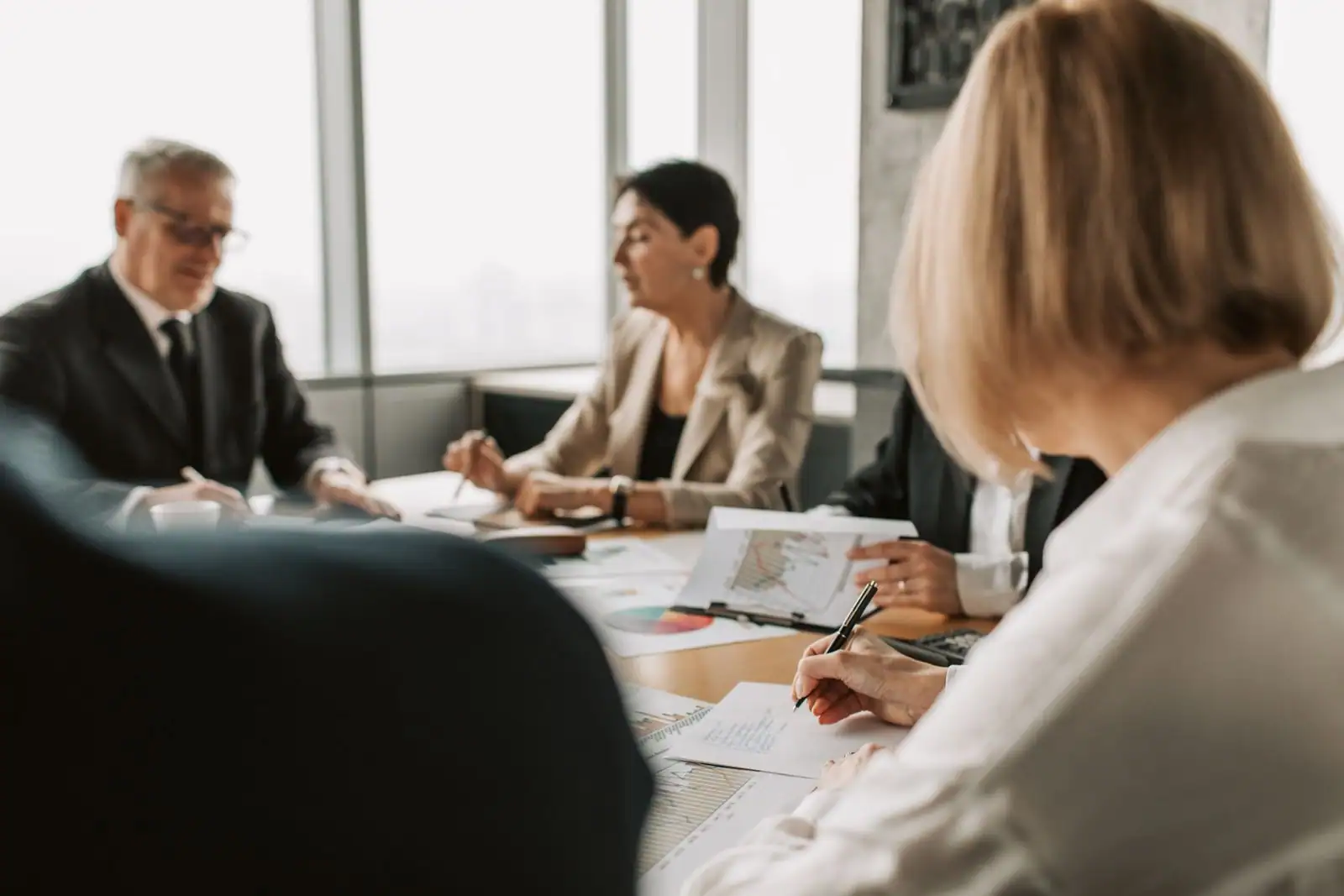 Réunion d'équipe autour d'une table dans des bureaux lumineux, échange de travail