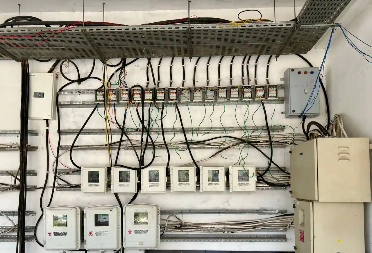 Installation électrique murale avec une rangée de disjoncteurs, des compteurs et de nombreux fils raccordés