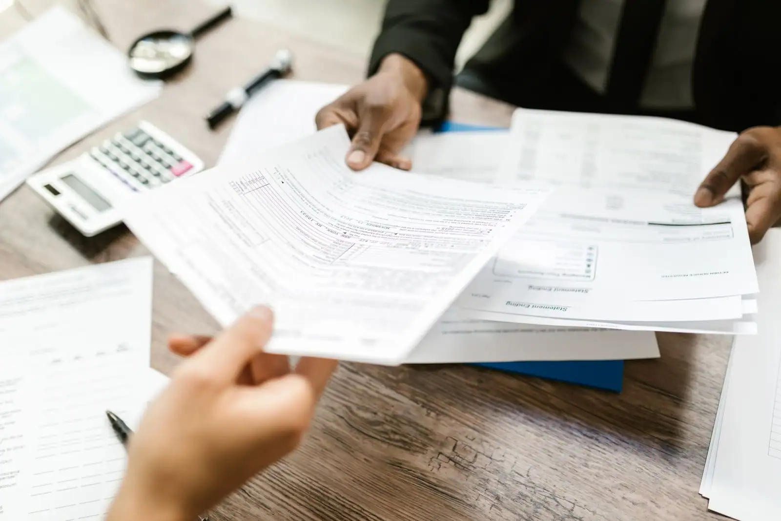 Remise de documents administratifs au-dessus d'un bureau, près d'une calculatrice
