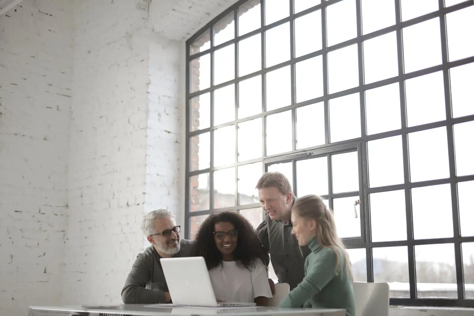 Équipe d'une jeune entreprise réunie autour d'un ordinateur portable dans un bureau