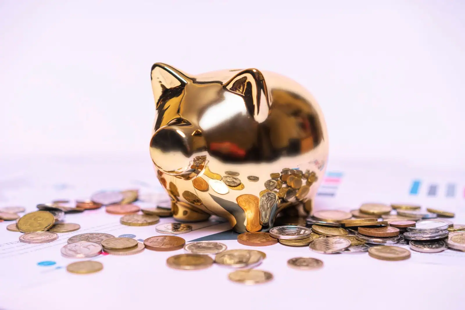 Tirelire dorée en forme de cochon entourée de pièces de monnaie, illustrant l'épargne