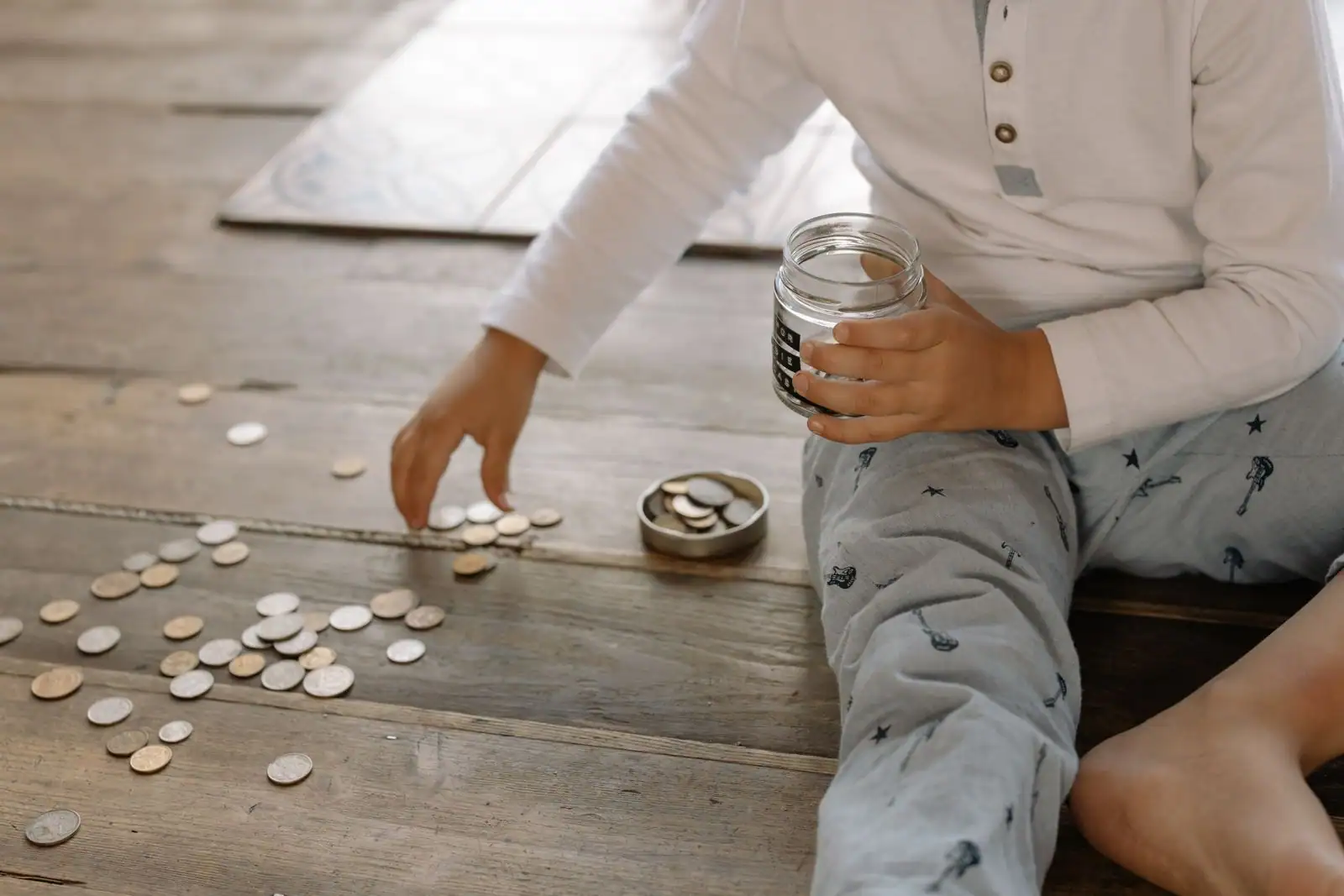 Enfant rassemblant des pièces de monnaie dans un bocal en verre, sur le thème de l'épargne