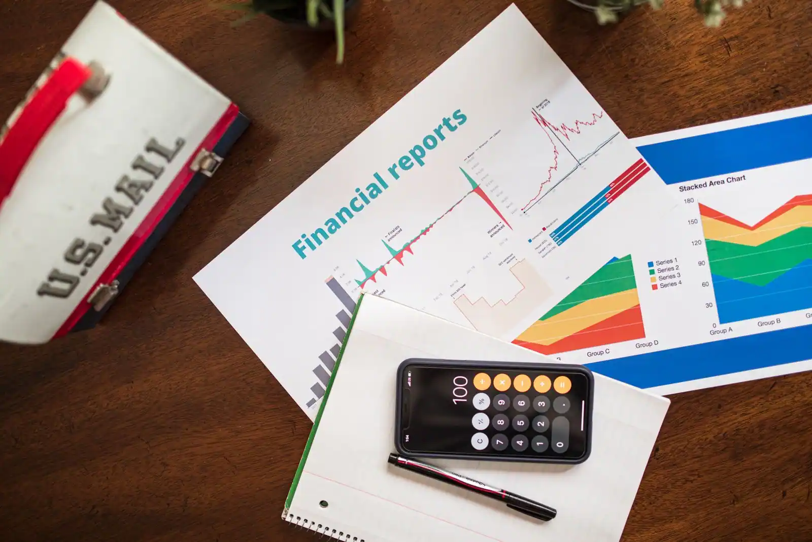 Documents de rapports financiers avec graphiques, calculatrice et stylo sur un bureau, illustrant la finance d'entreprise.