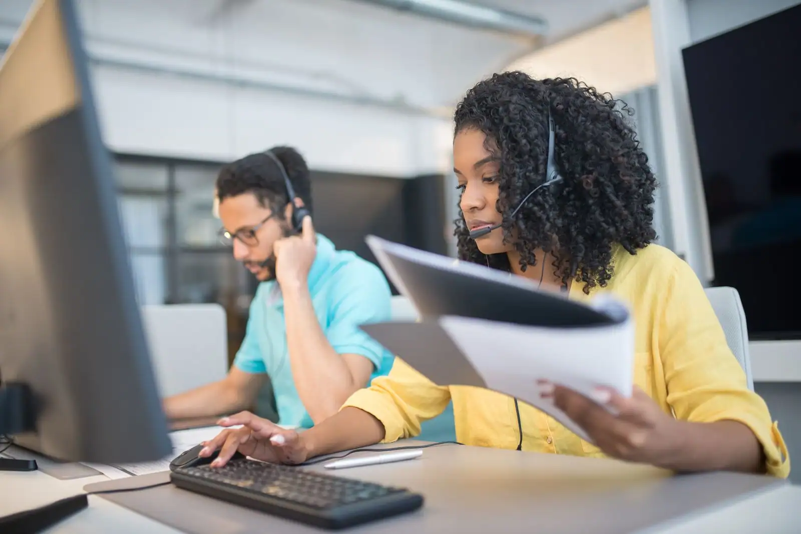 Conseillers clientèle équipés d'un casque audio à leur poste dans un centre de relation client