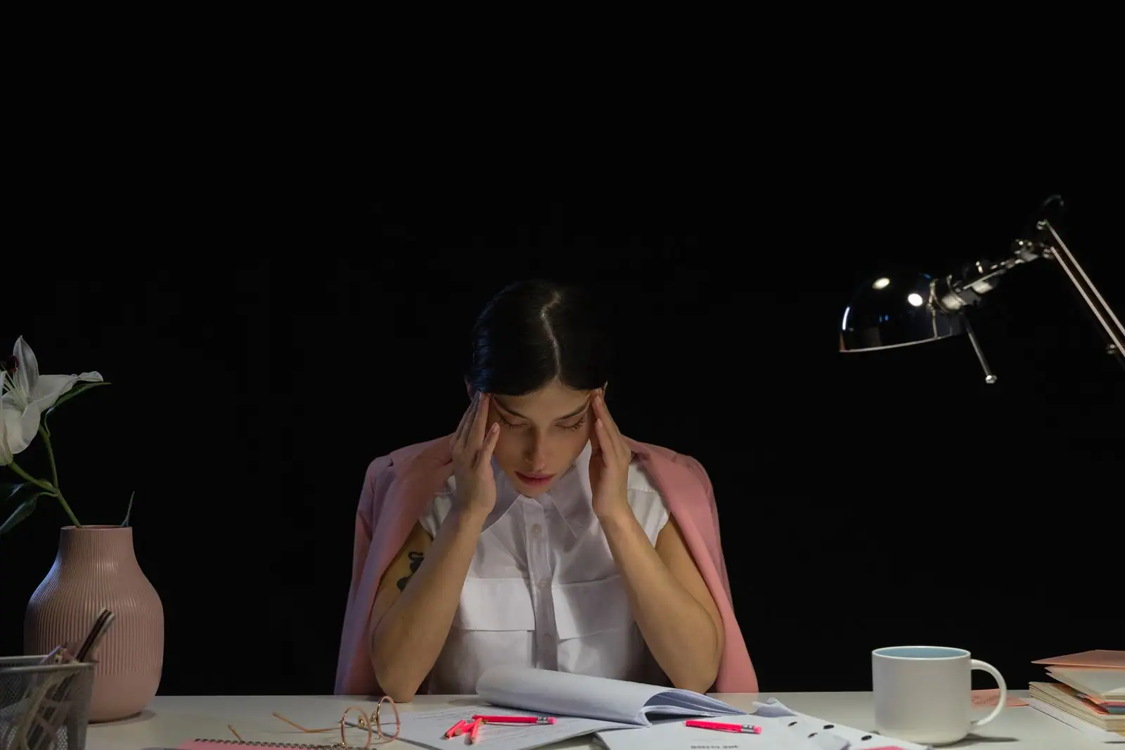 Personne tendue à son bureau, mains sur les tempes, penchée sur des documents