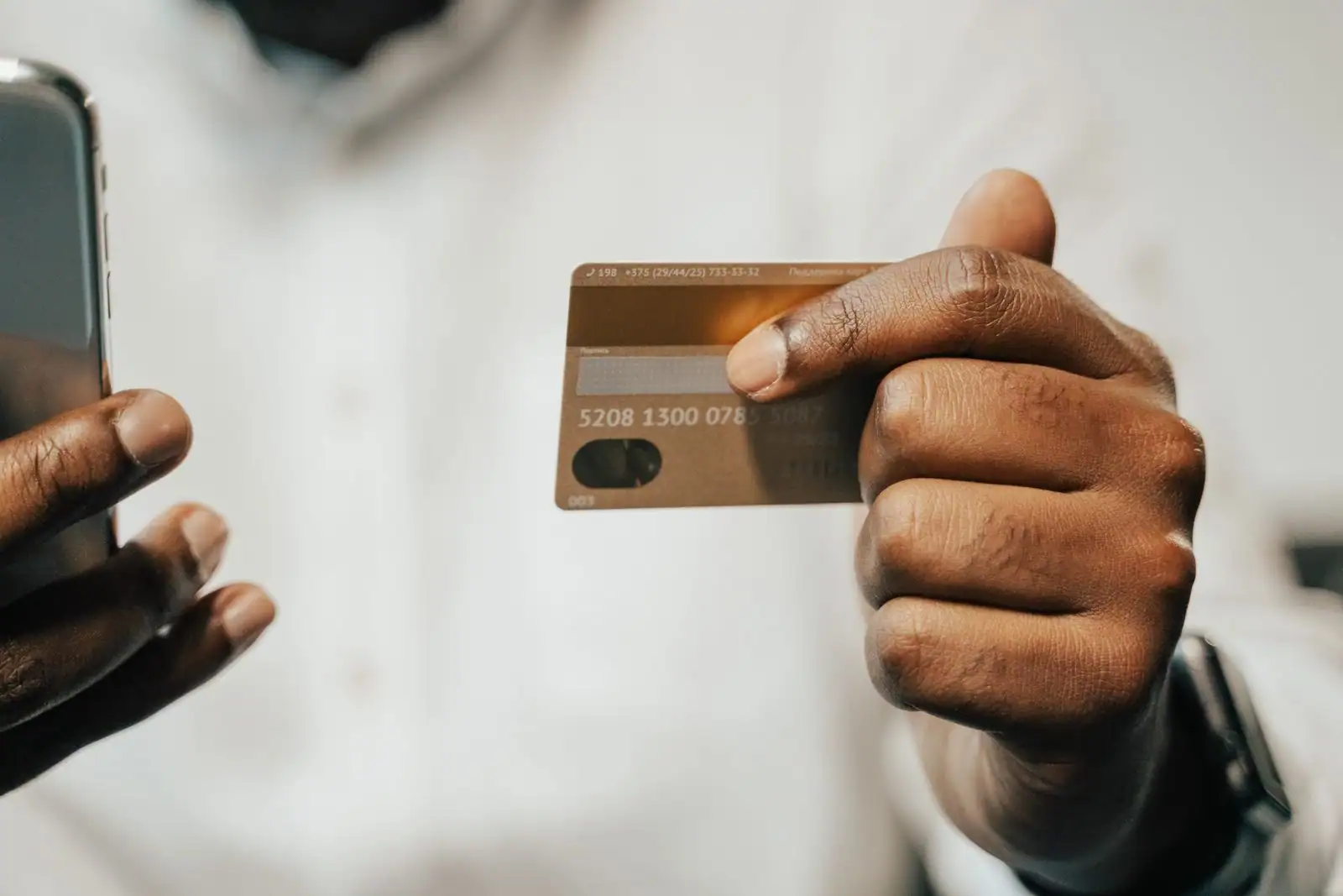 Personne consultant une application bancaire sur son smartphone, carte de paiement à la main