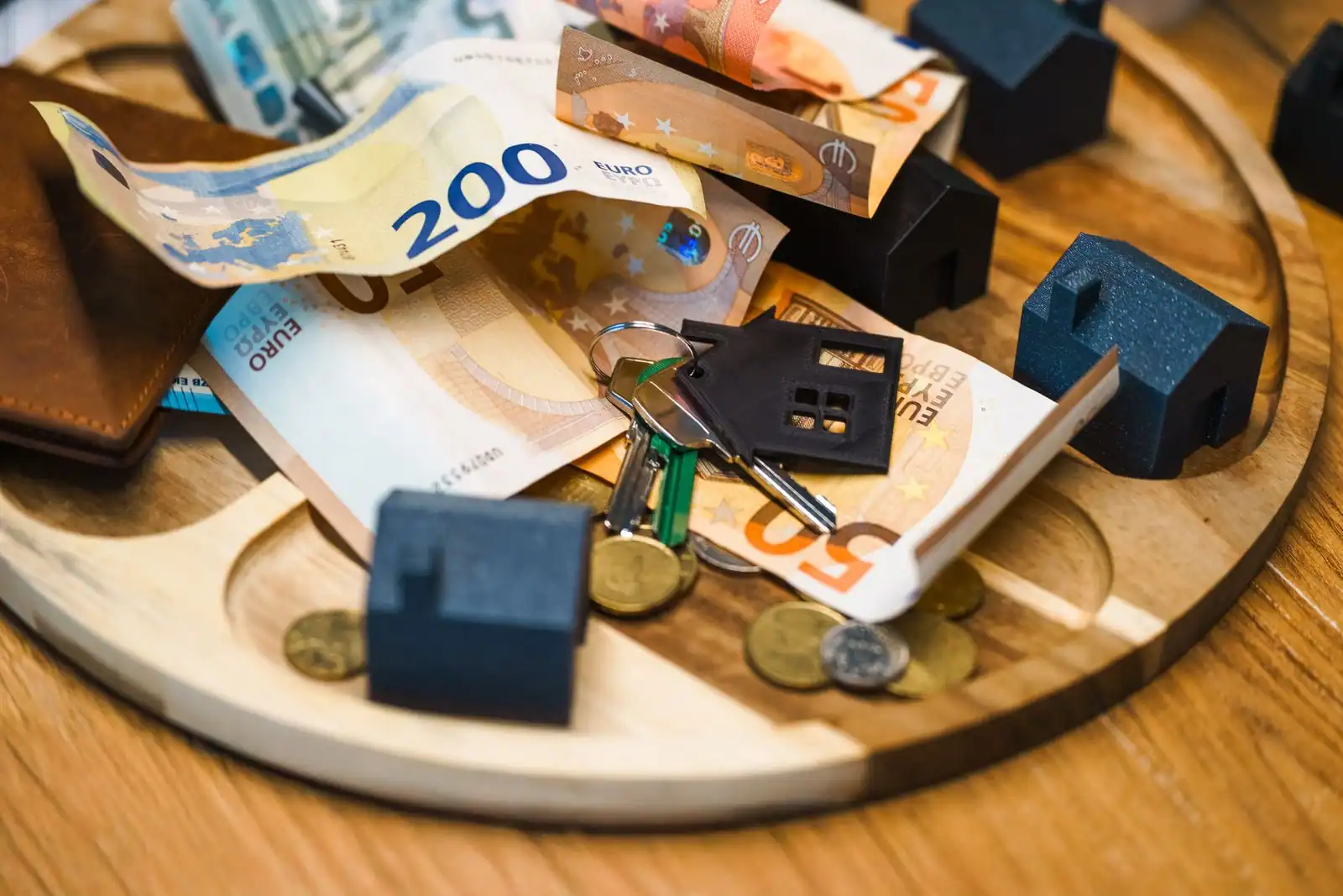 Billets en euros, pièces, clés et maisons miniatures évoquant l'épargne en vue d'un logement