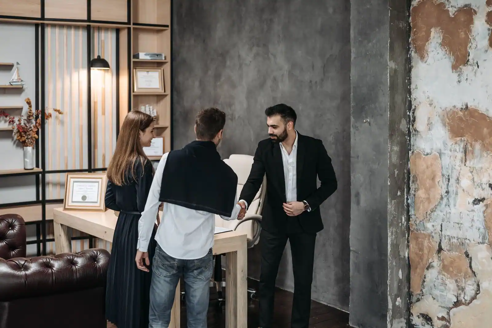 Réunion de travail entre trois personnes dans un bureau au style industriel, avec une poignée de main