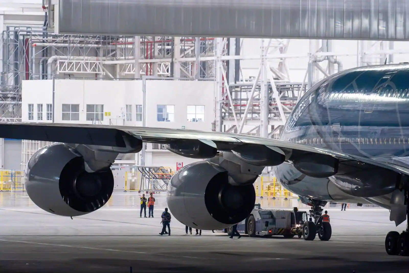 Un avion de ligne et ses réacteurs sous l'aile, dans un hangar de maintenance aéronautique.