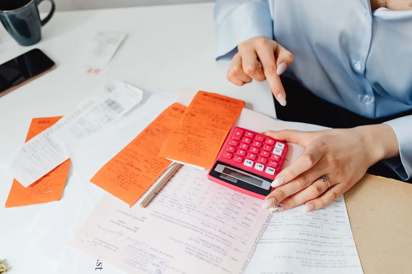 Calculatrice, reçus et documents comptables sur un bureau, évoquant le calcul des frais déductibles