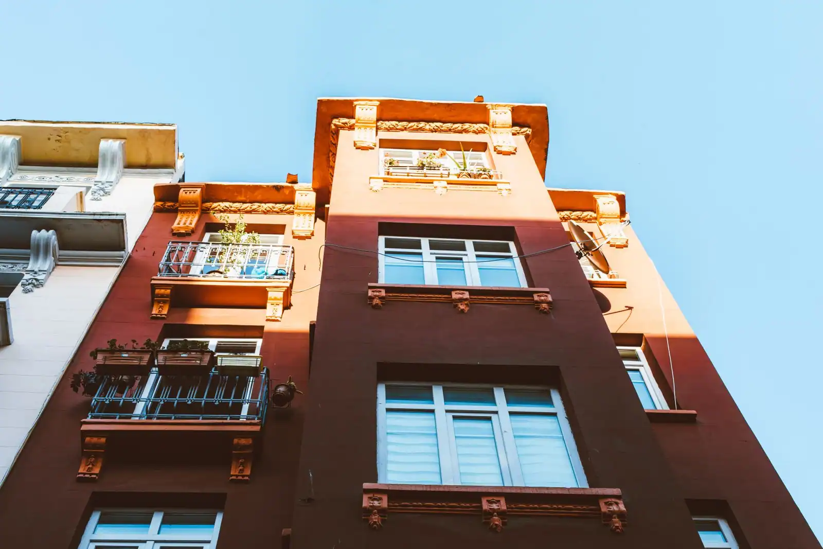 Façade d'un immeuble résidentiel ancien avec ses balcons et ses fenêtres, vue en contre-plongée.