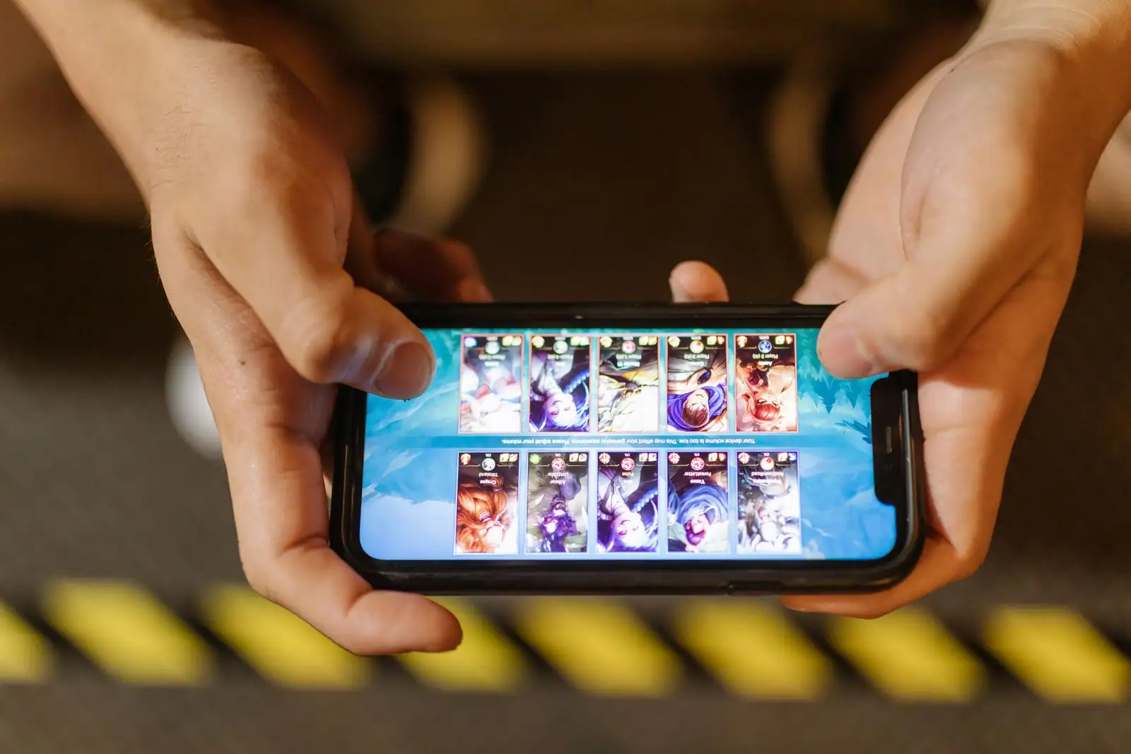 Personne jouant à un jeu mobile sur son smartphone, écran lumineux tenu à deux mains
