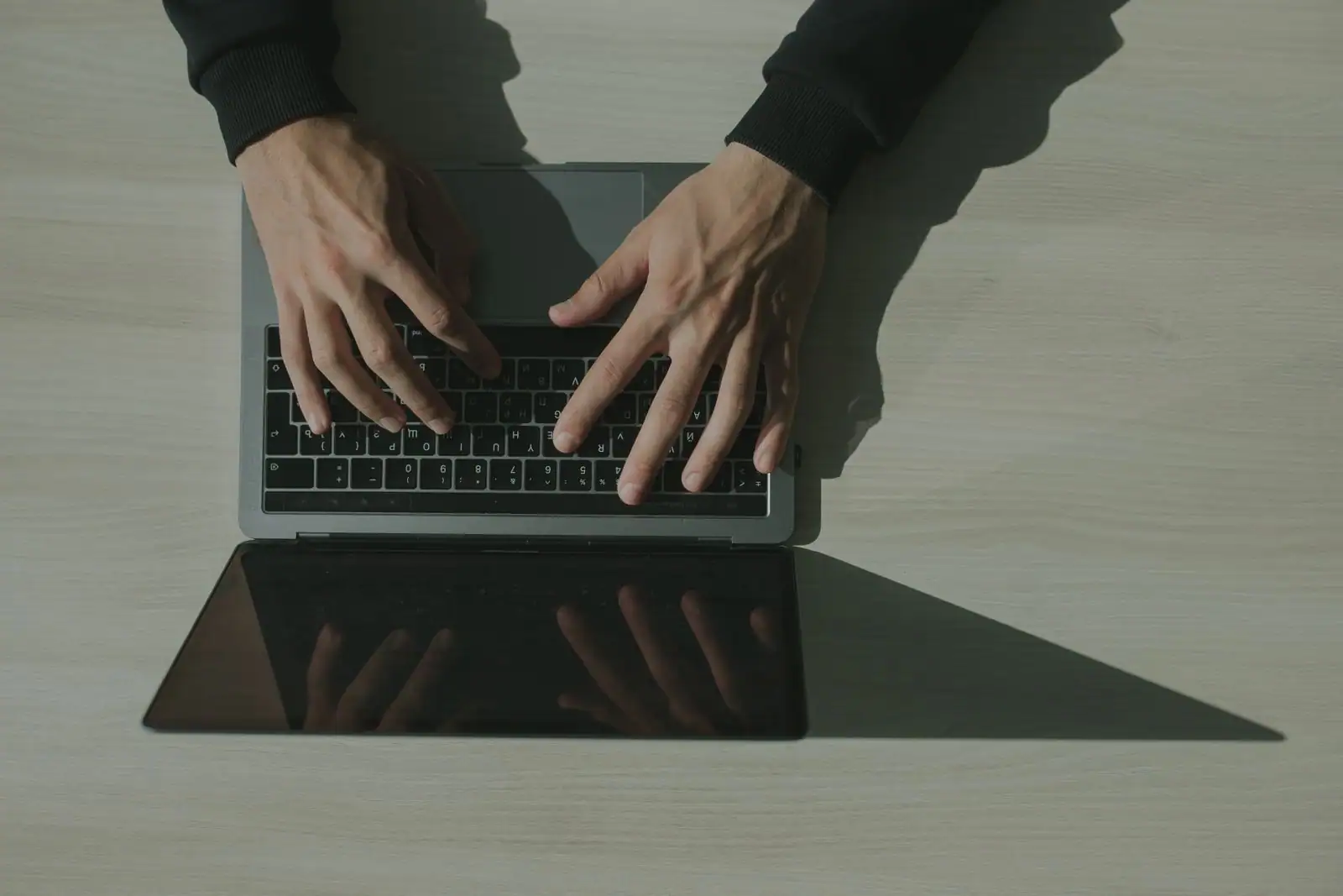 Mains d'une personne tapant sur le clavier d'un ordinateur portable, vue de dessus