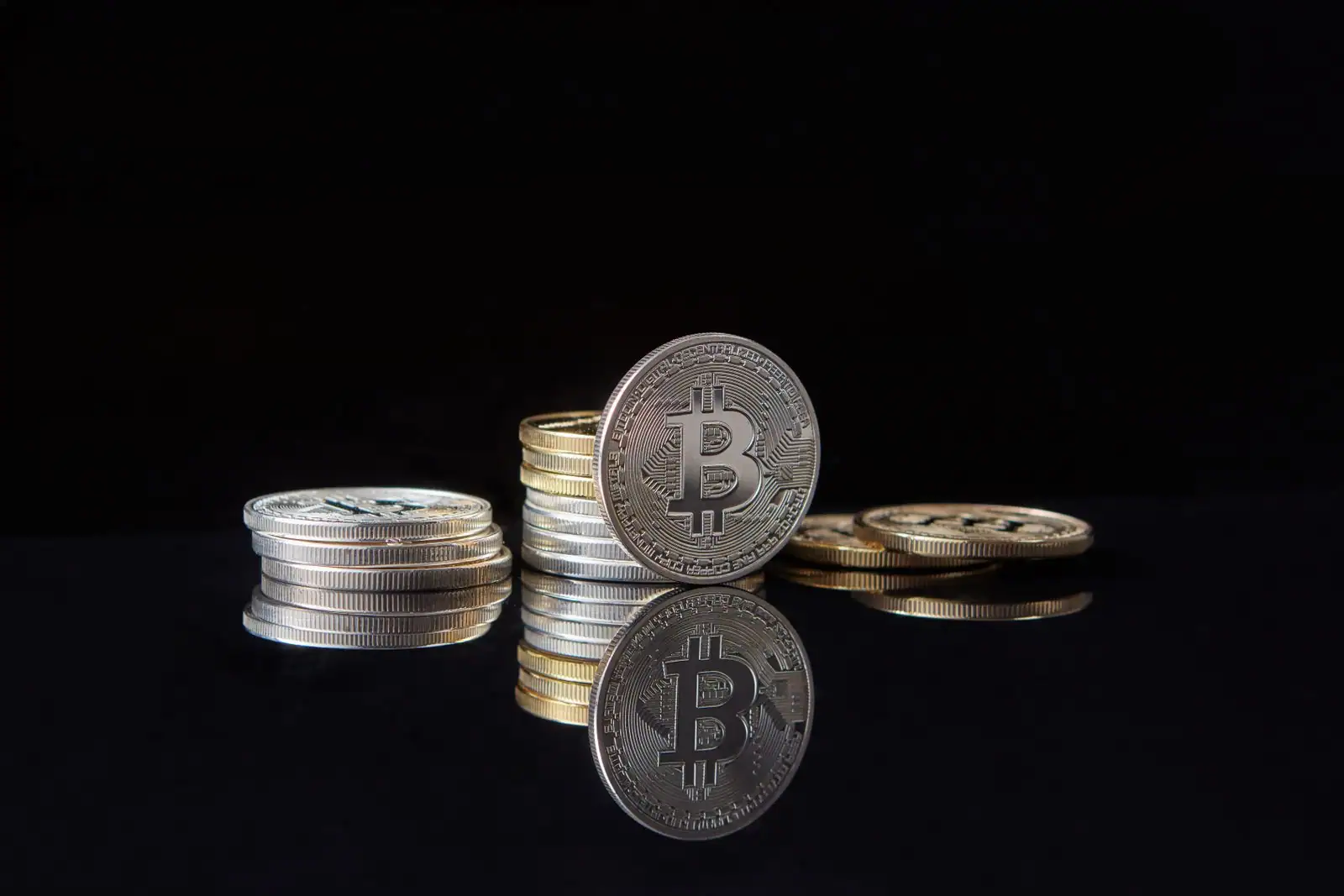 Pièces physiques de cryptomonnaie bitcoin empilées sur la surface sombre d'un bureau