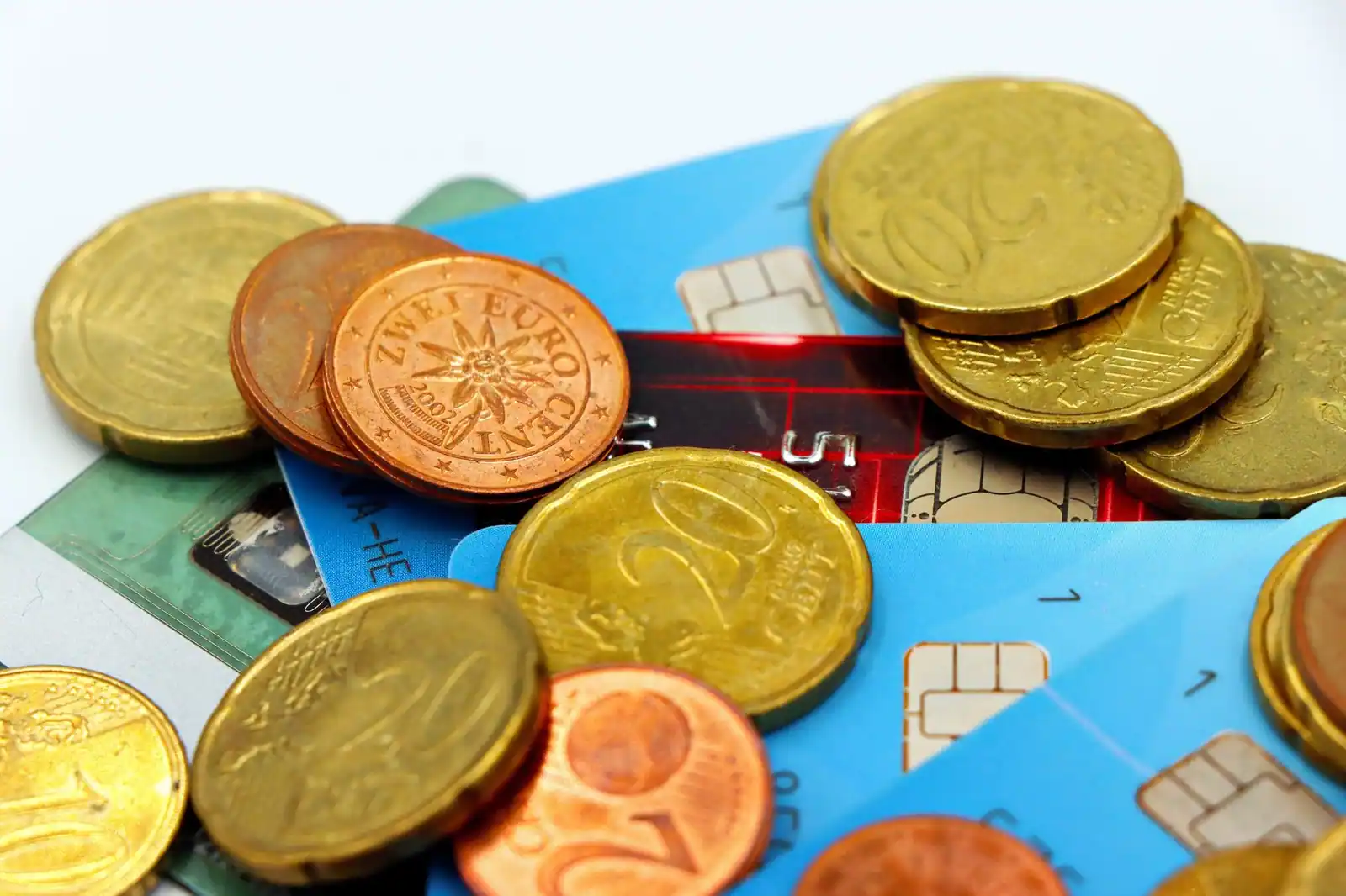 Cartes bancaires à puce et pièces en euros mêlées, évoquant les frais liés à un compte courant