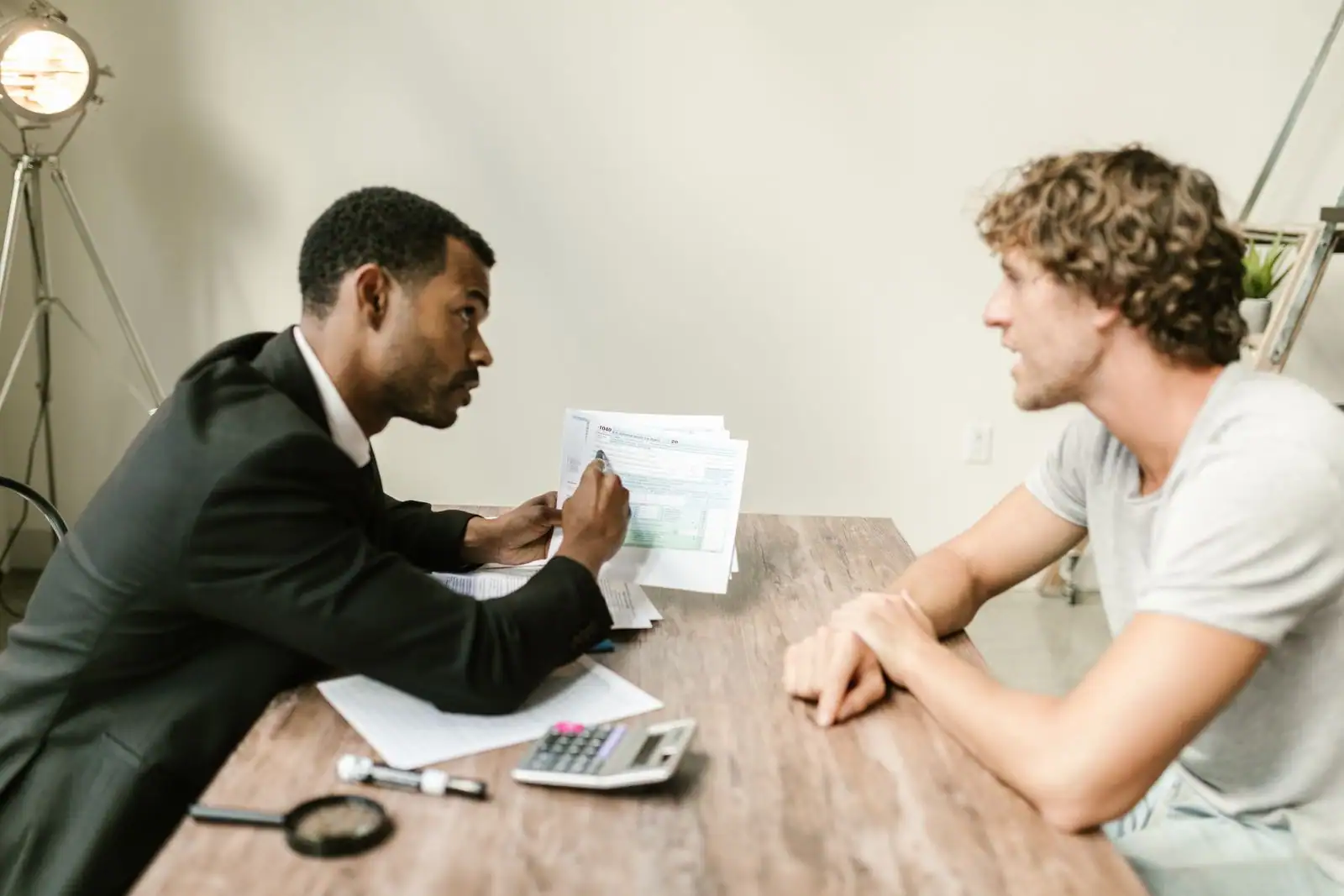 Un conseiller en gestion de patrimoine et son client examinent des documents financiers à un bureau.