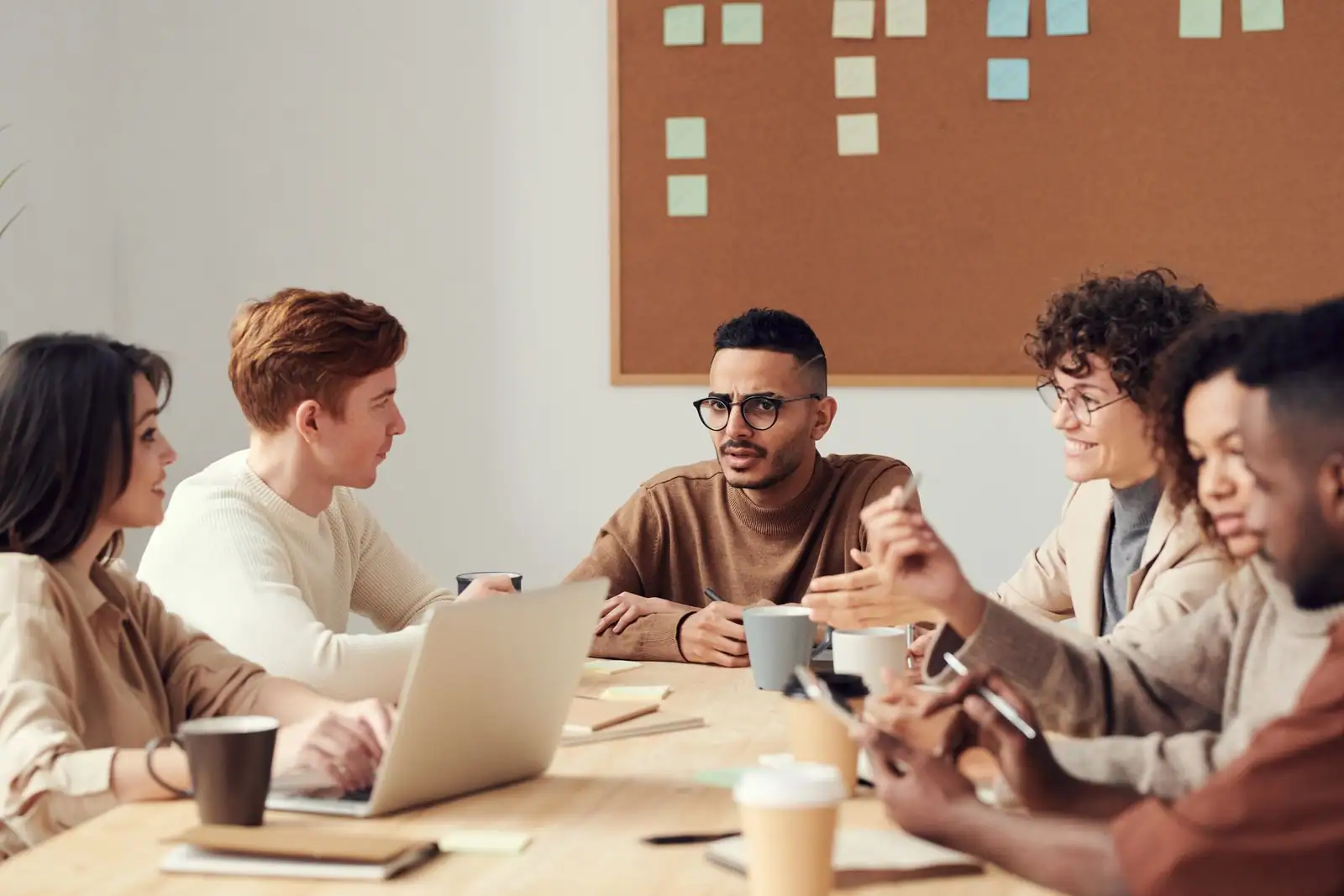 Une équipe de collaborateurs échange autour d'une table dans un bureau, illustration de la gestion RH