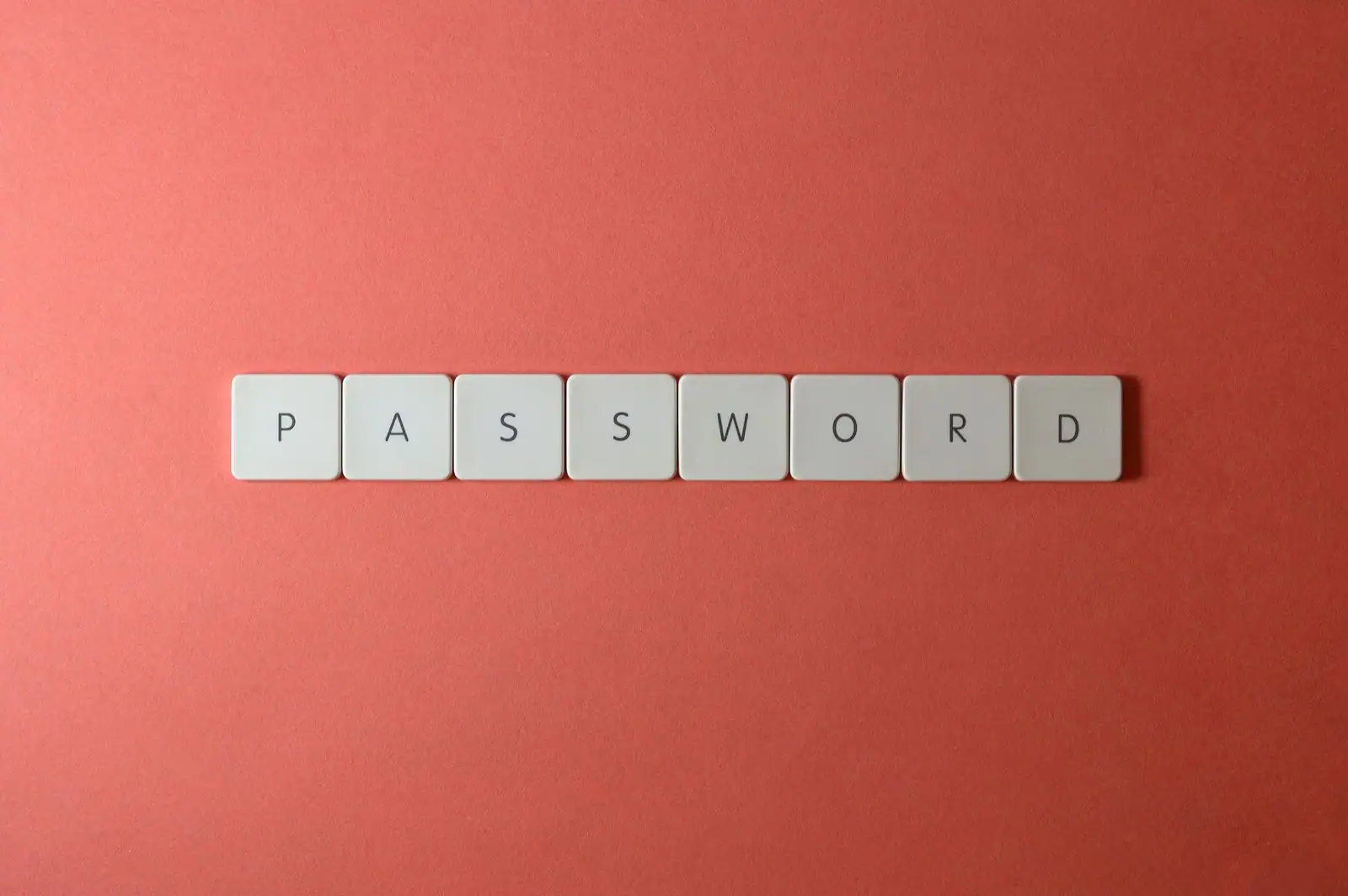 Lettres blanches formant le mot « password » sur un fond corail, évoquant la gestion des mots de passe