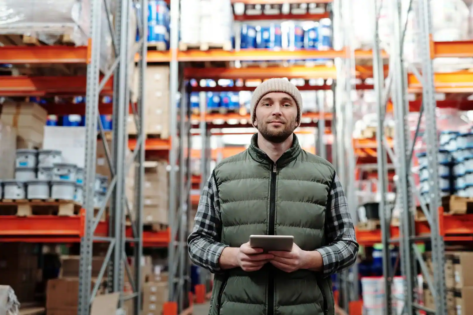 Employé vérifiant un stock sur une tablette numérique dans les rayonnages d'un entrepôt