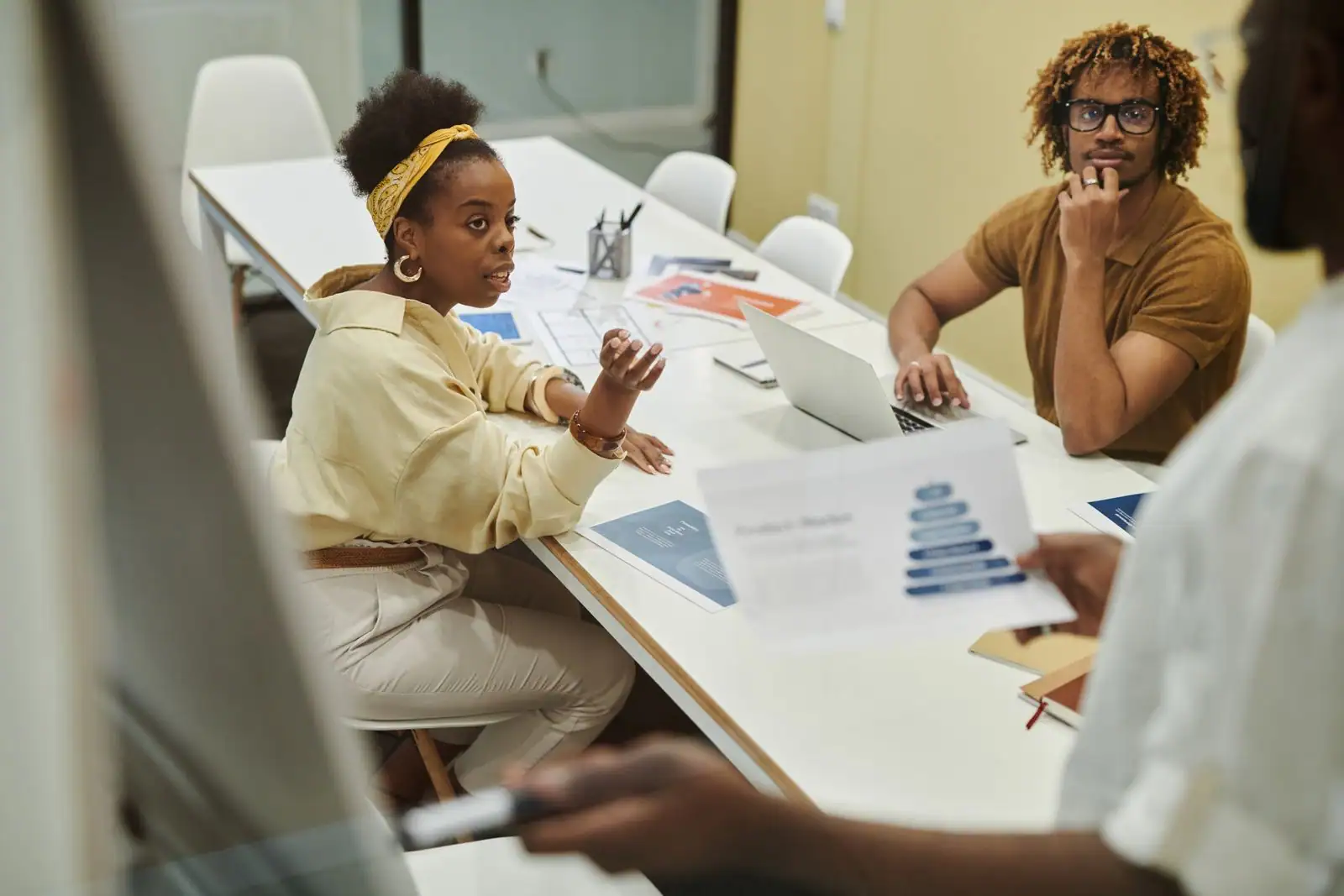 Équipe réunie autour d'une table de travail avec des documents lors d'une réunion.