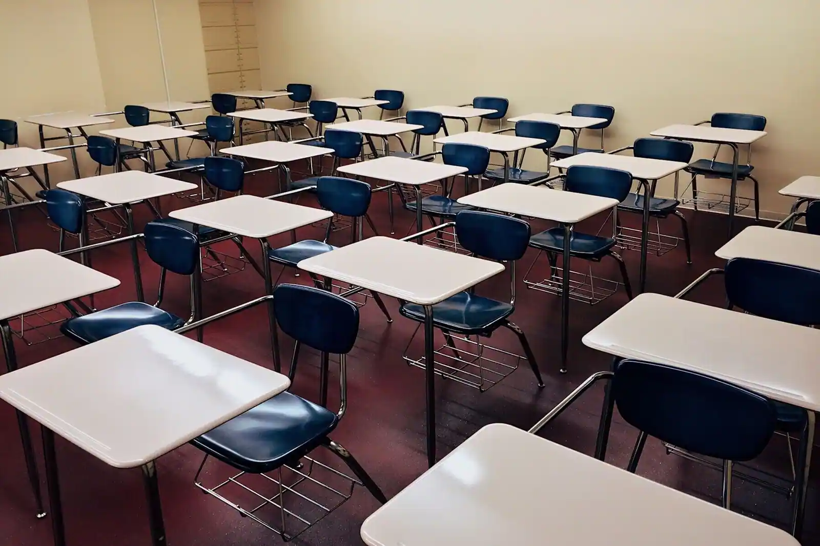 Une salle aux rangées de pupitres vides, évoquant une session de concours ou d'examen.