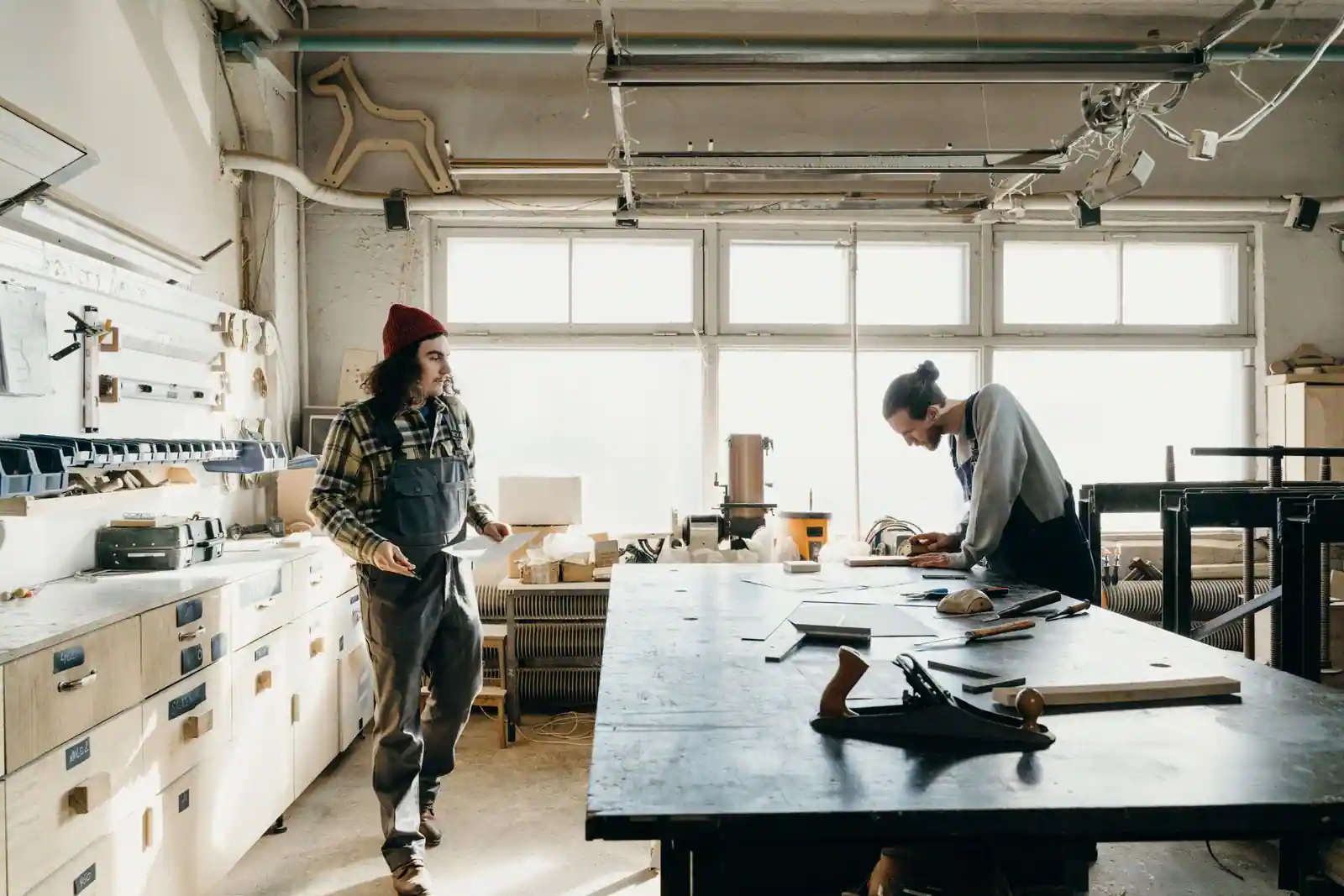 Adulte en reconversion apprenant un métier artisanal du bois dans un atelier lumineux