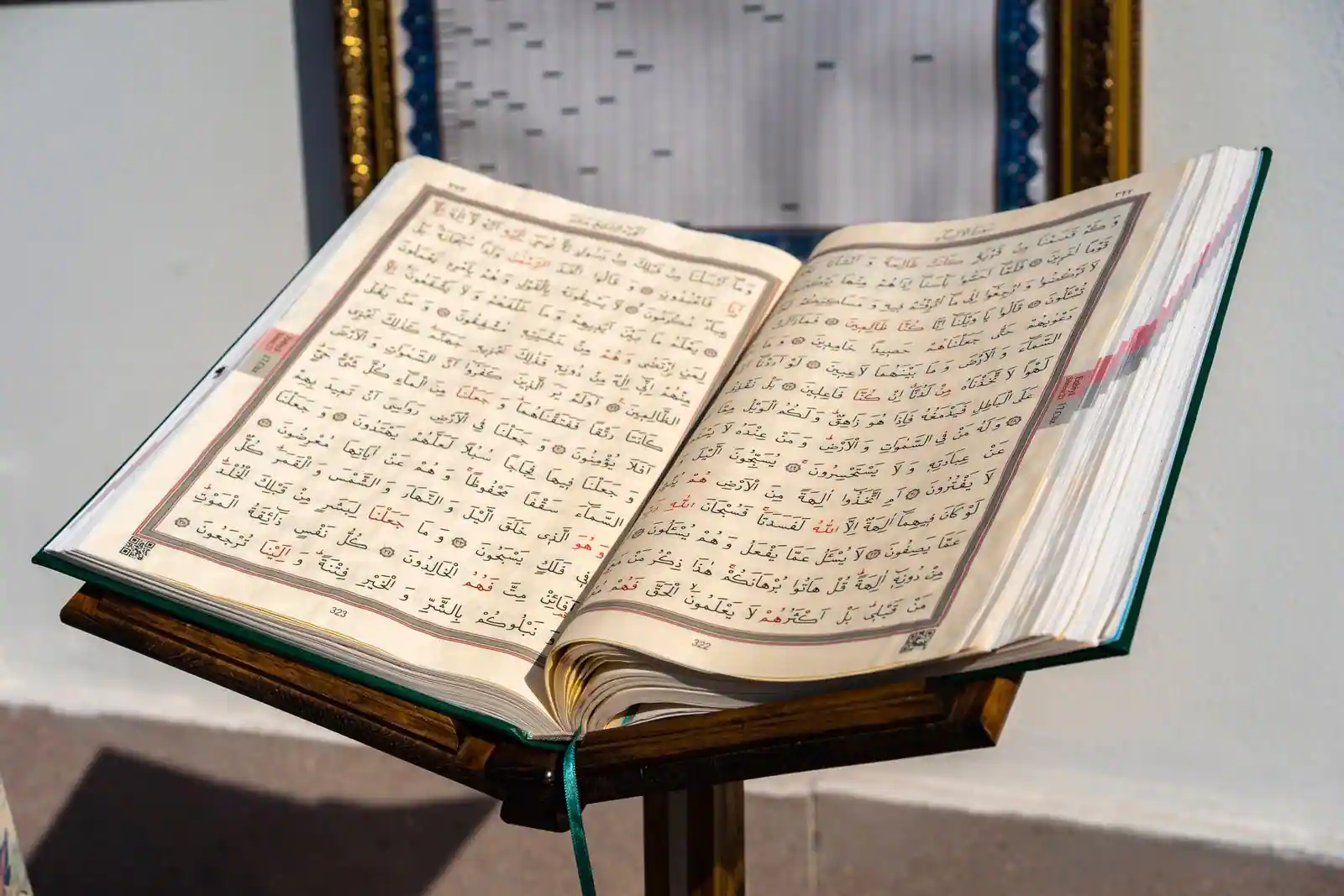 Exemplaire ouvert du Coran, texte en arabe, posé sur un lutrin en bois sculpté