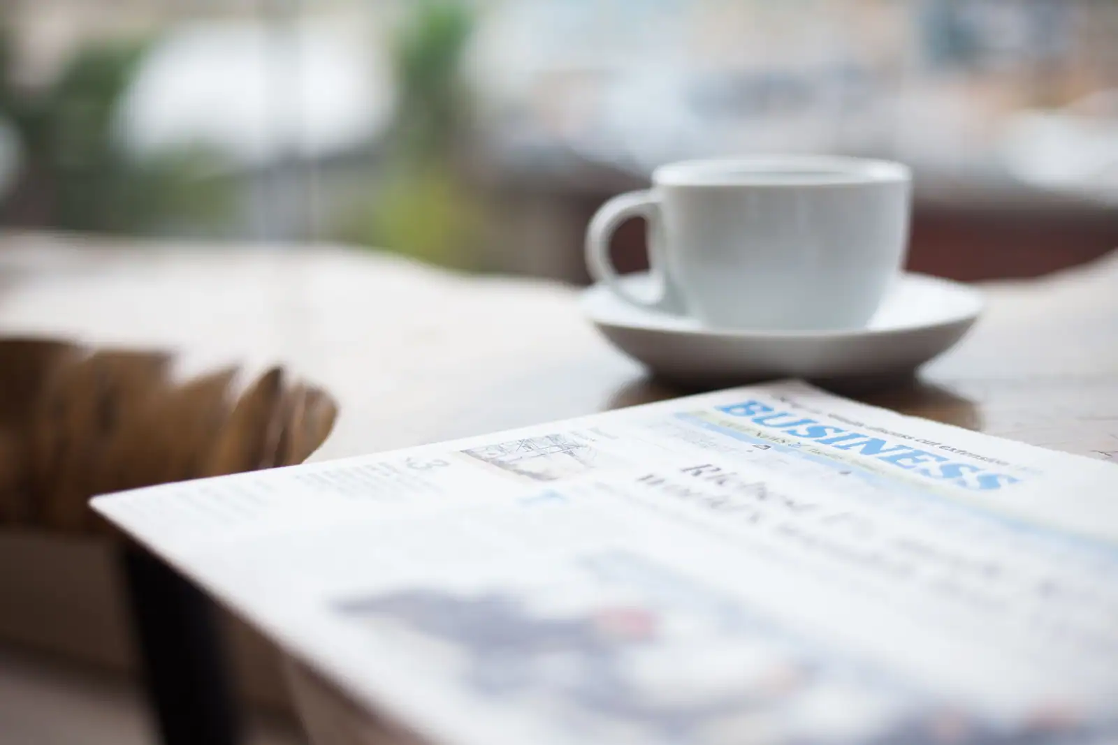Un journal ouvert à la rubrique économie posé près d'une tasse de café sur une table