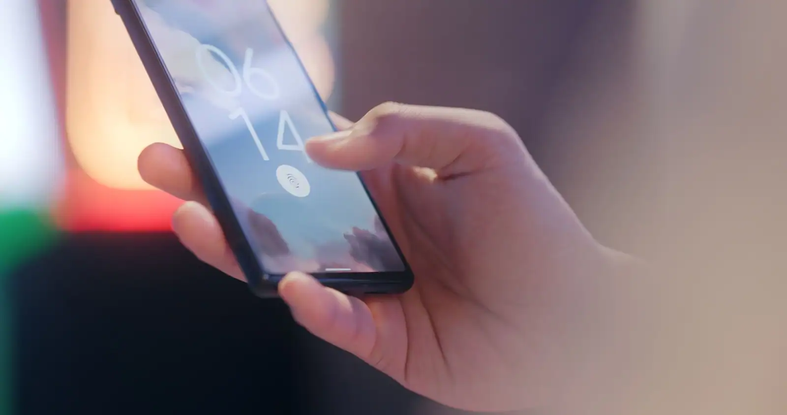 Doigt approchant le capteur d'empreinte d'un smartphone sur son écran de verrouillage.