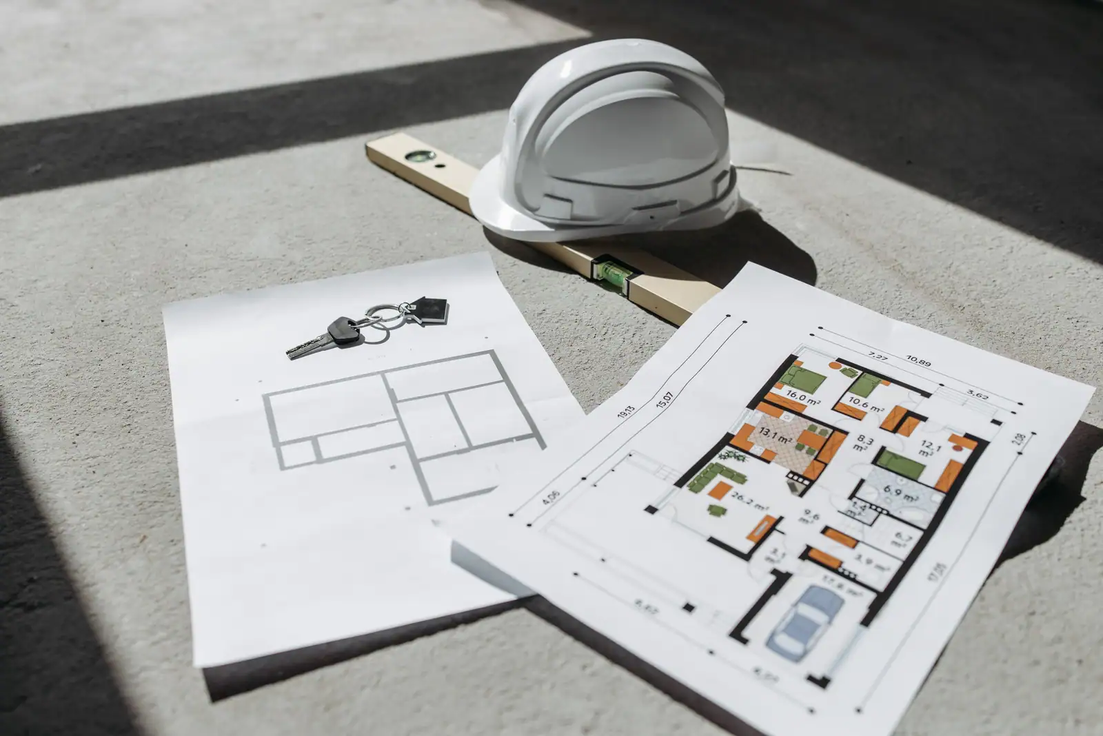 Plans de logement, casque de chantier et clés posés au sol, éléments concrets d’un programme immobilier neuf