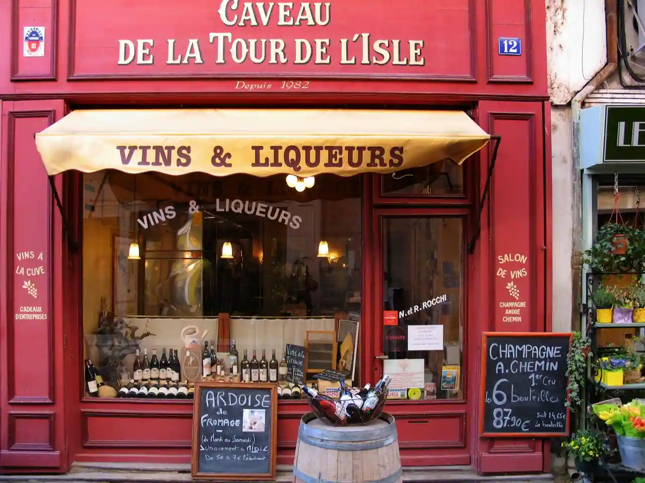 Devanture rouge d'un caviste de centre-ville, enseigne peinte, store marqué et ardoises manuscrites.