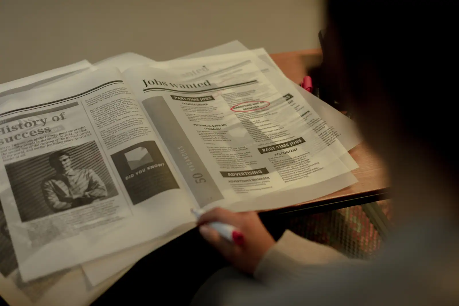 Une personne entoure au marqueur une annonce dans la rubrique emploi d’un journal ouvert.